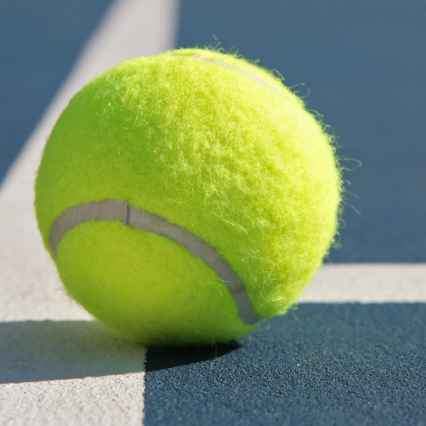 Yellow tennis ball on a tennis court floor