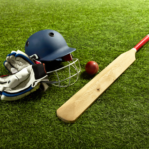 Cricket bat, ball, hat and gloves laid out on the grass
